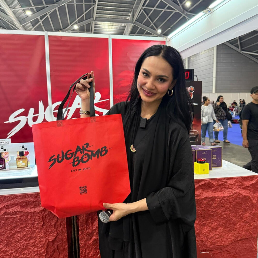 Experiencing the best of SugarBomb SG at local beauty and fragrance events. A model presenting a SugarBomb SG shopping bag, featuring the best perfume store deals for long-lasting fragrances in Singapore.